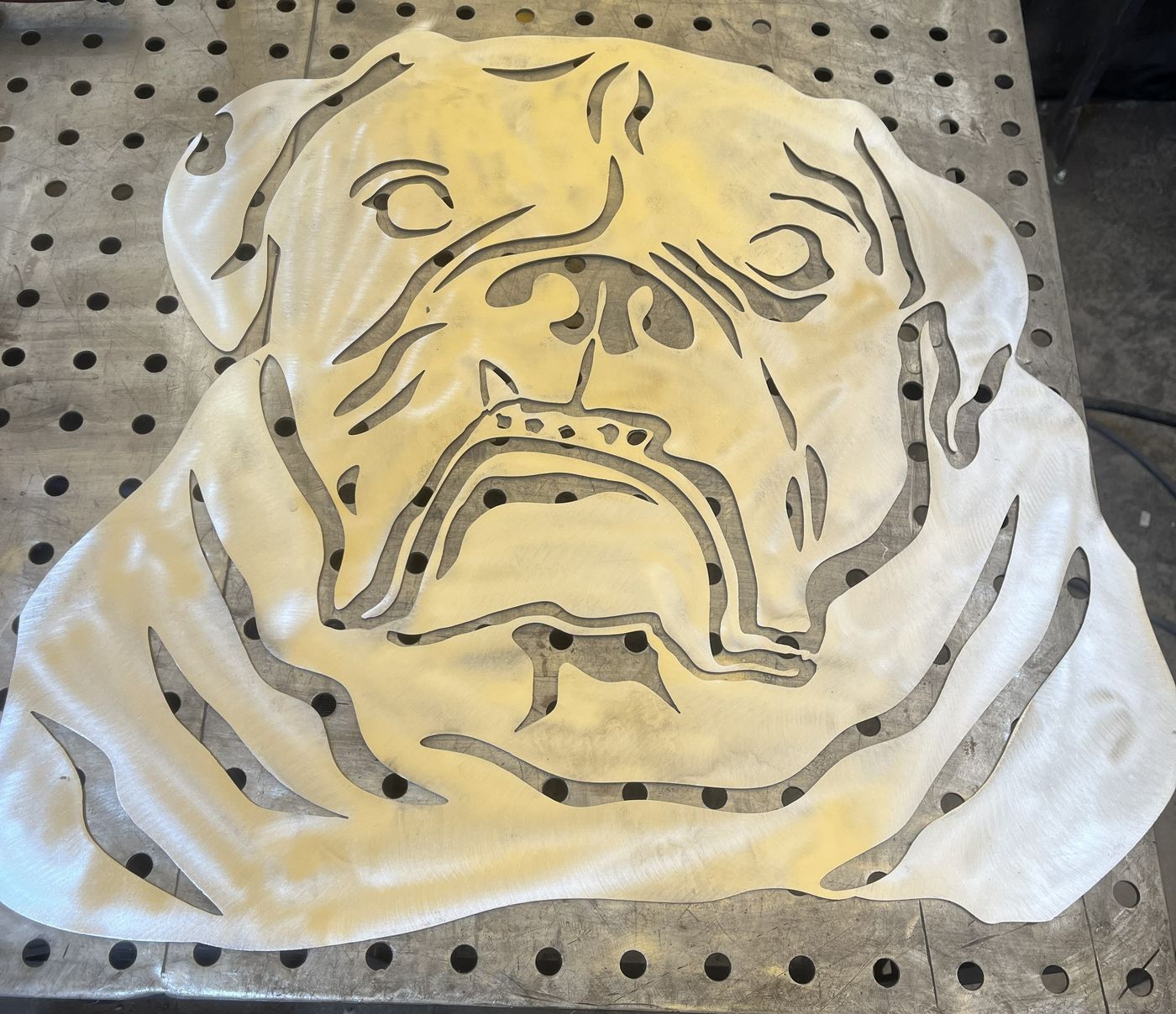 Plasma-cut bulldog face resting on a fixture welding table