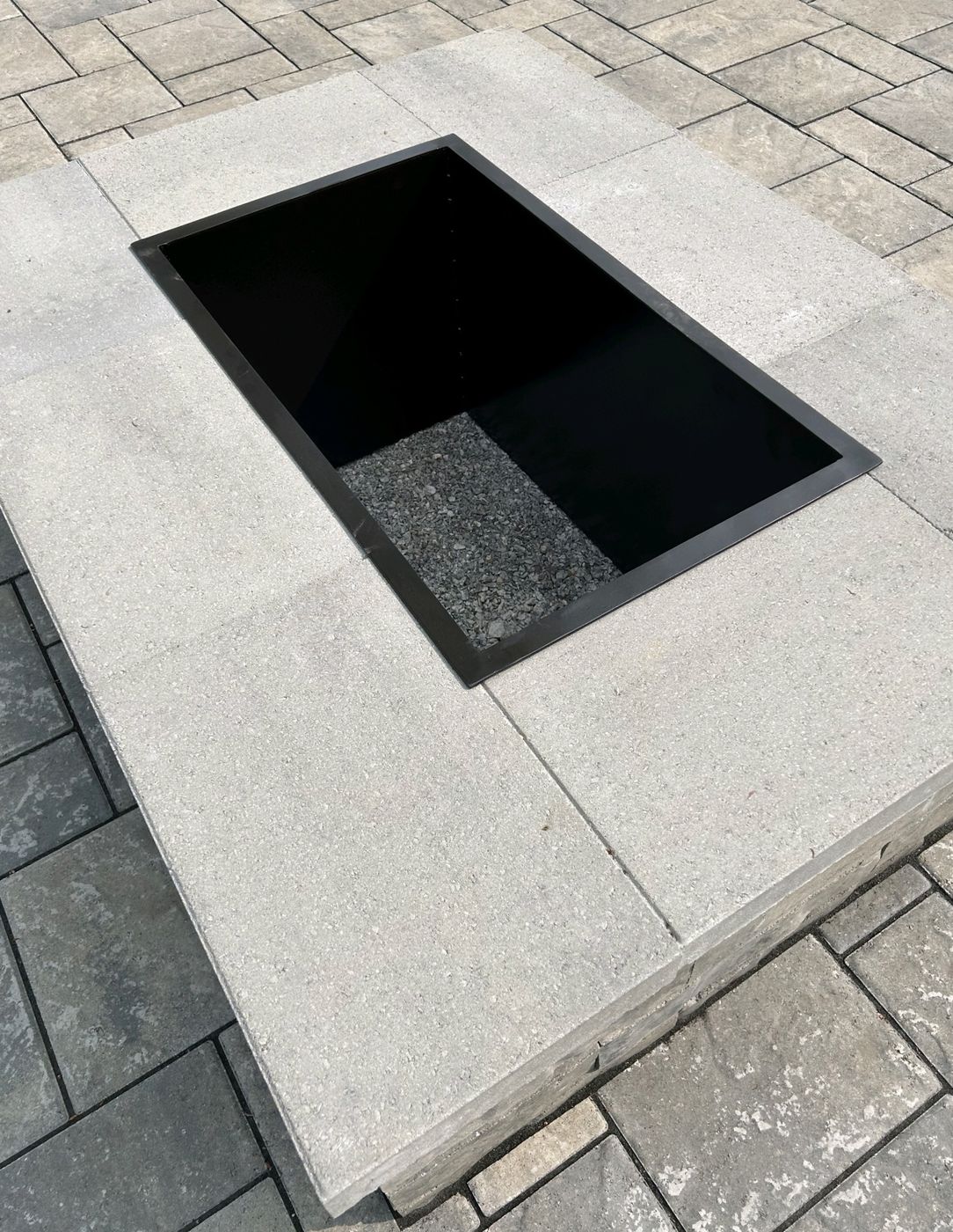 Rectangular steel fire pit liner set flush into a paver patio