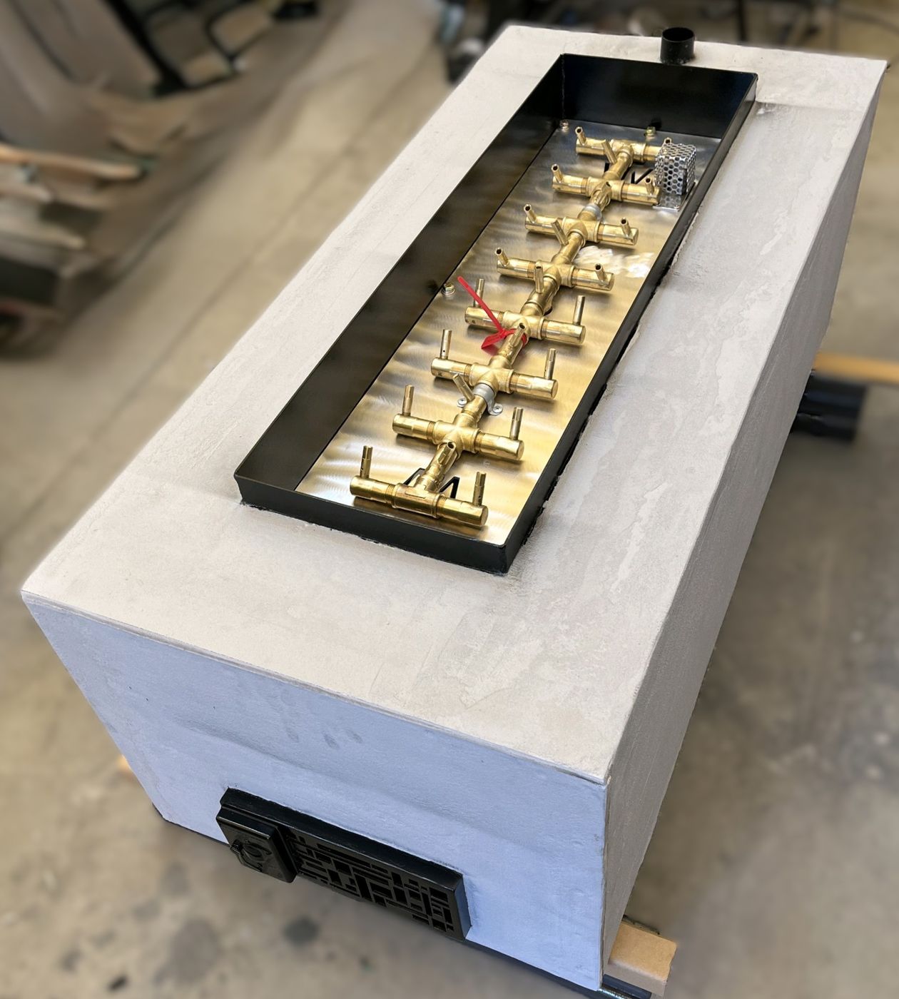 Custom gas fire table with a brass crossfire burner and concrete-look surround