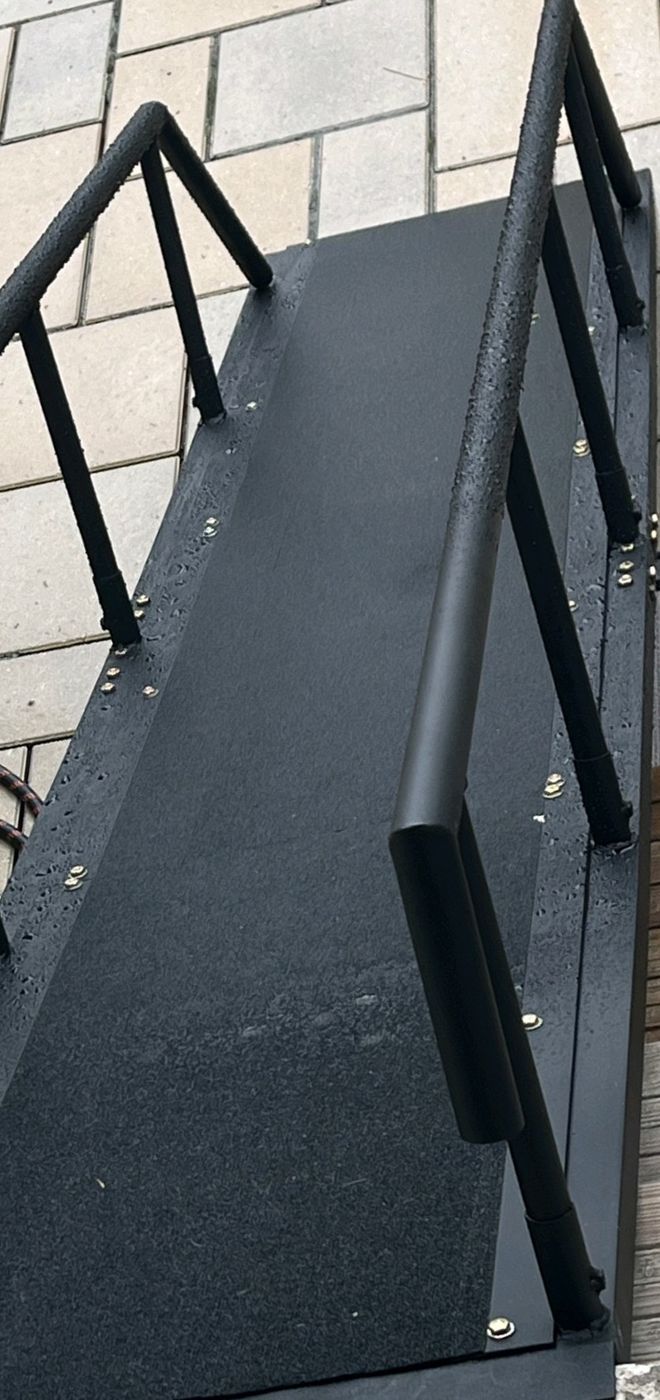 Fabricated steel access ramp with welded handrails and a non-slip coating