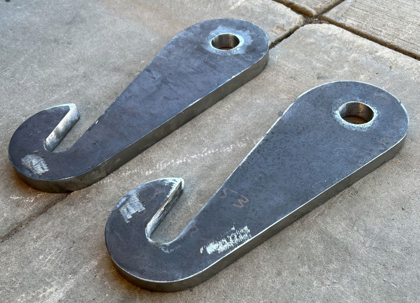 A matched pair of cut steel brackets with hook slots and bolt holes