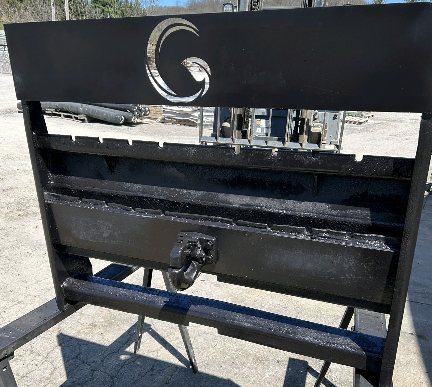 Custom skid steer attachment with a logo cut into the face panel