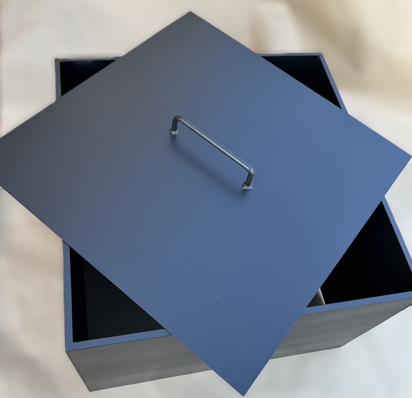 Welded square steel fire pit with a fitted lid and bent-rod handle