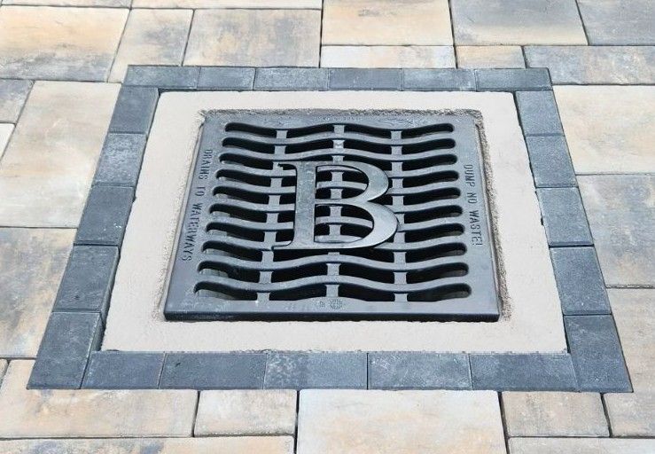 Custom monogram storm drain grate set in pavers
