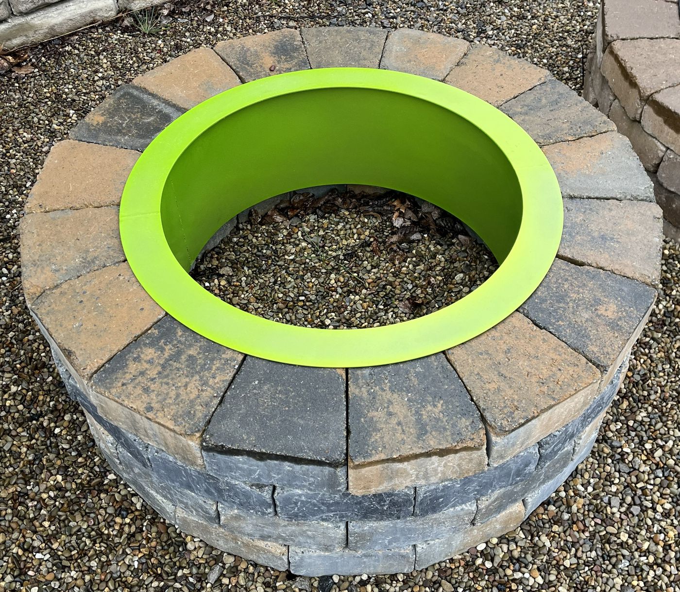 Lime green powder-coated steel fire pit ring set into a paver fire pit